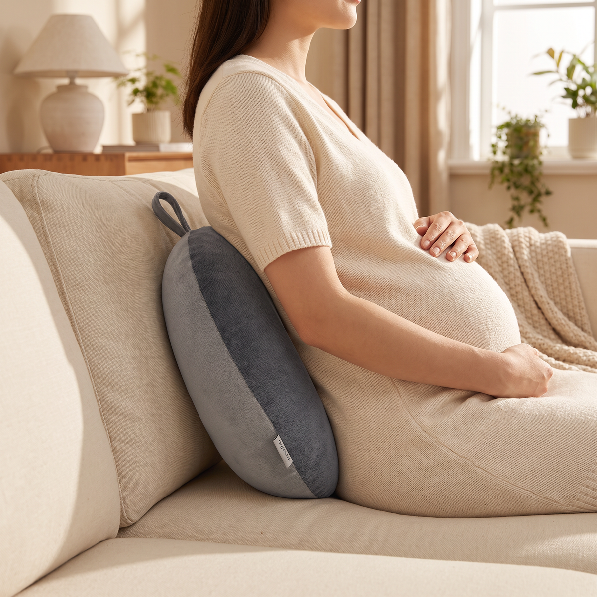 Bead-filled bolster supporting the lower back of a pregnant woman seated on a sofa