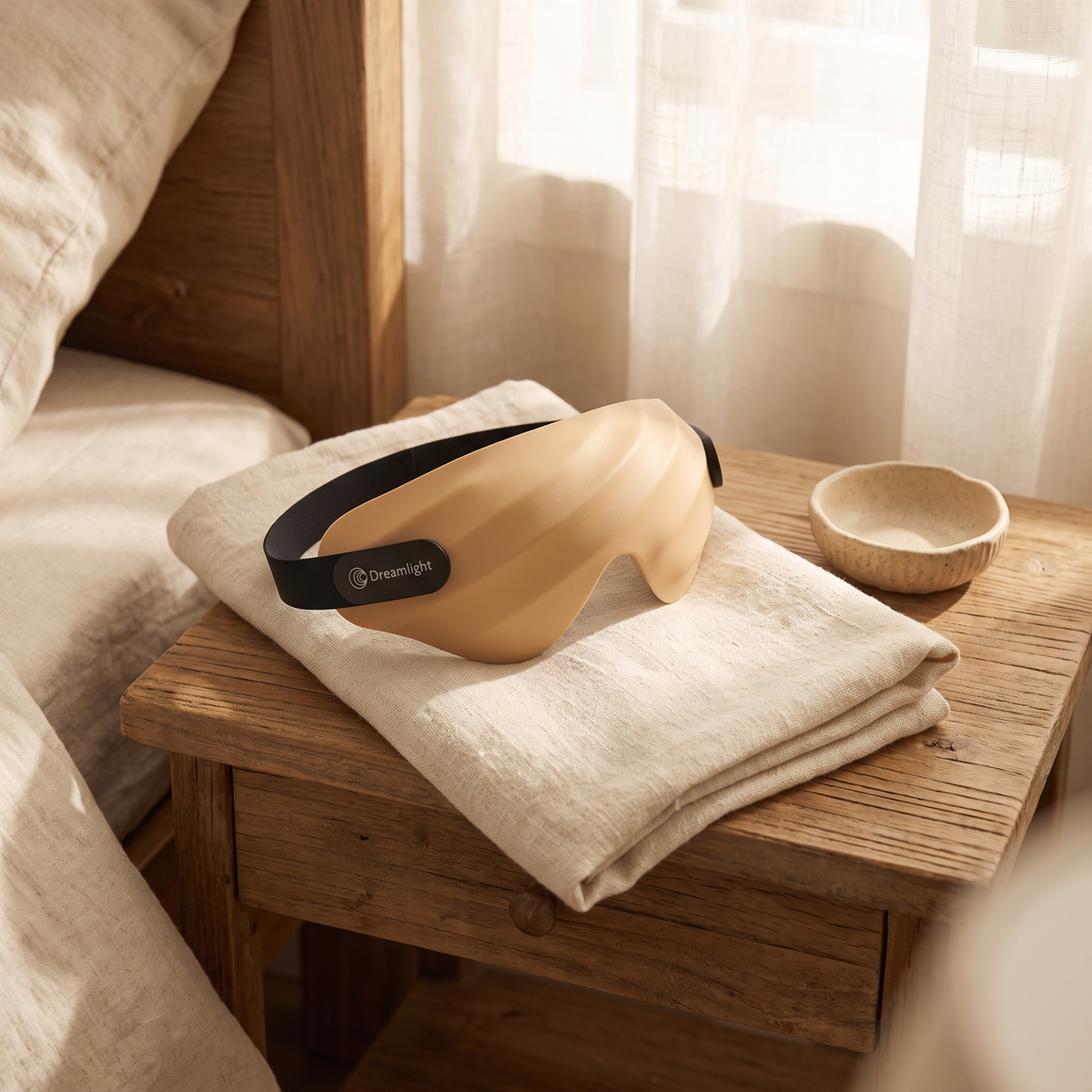Dreamlight 4S sleep mask resting on a folded cream towel on a nightstand
