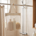 Mesh shower bag hanging from a shower rail in a bright bathroom