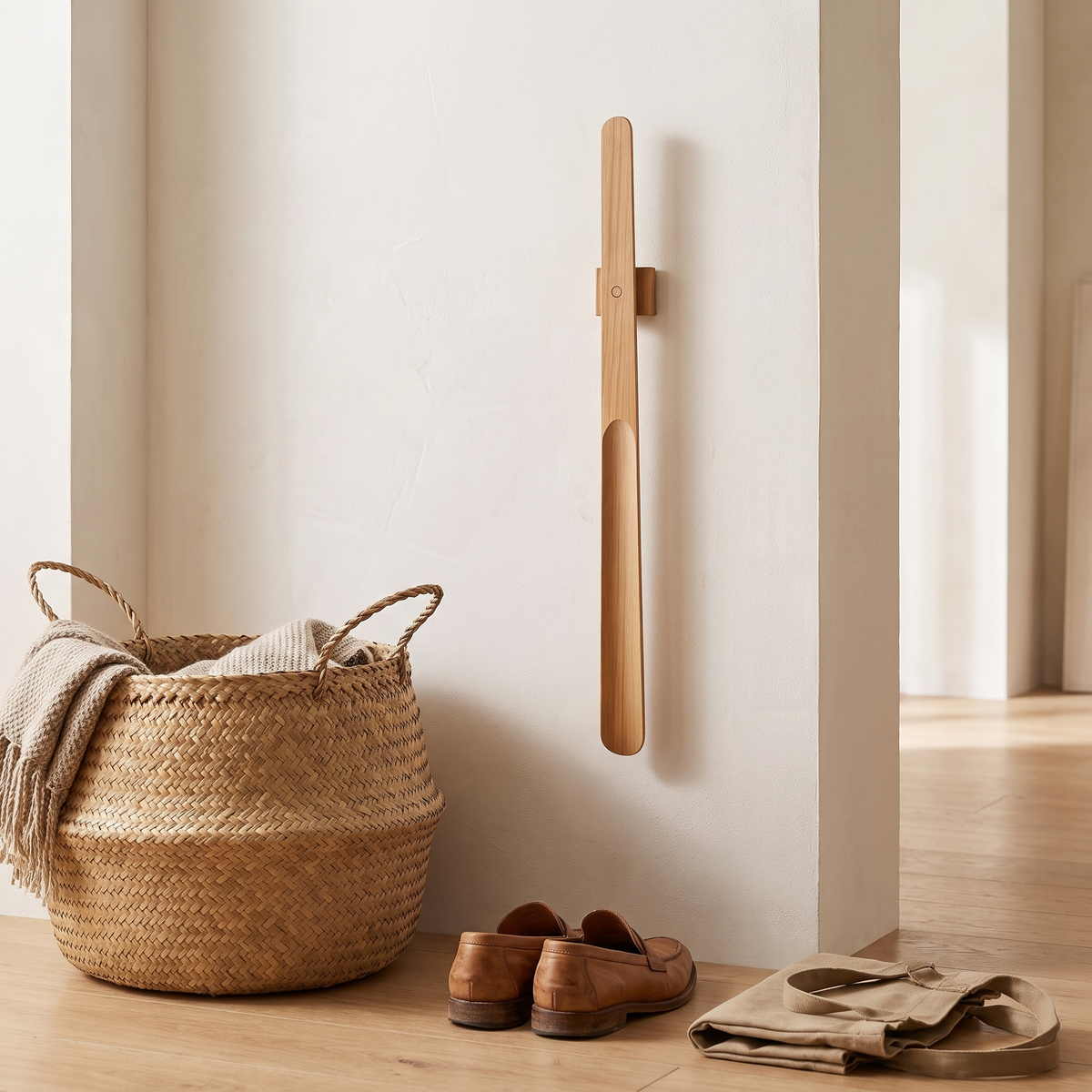 Long wooden shoe horn hanging by a wall beside a basket and shoes